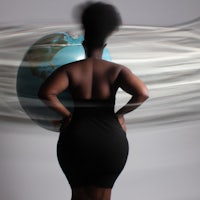a woman in a black dress standing in front of a globe