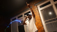 a man is holding a microphone in front of a brick wall